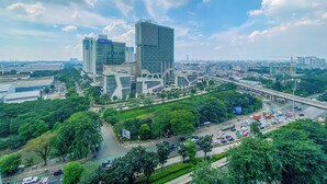 Un área urbana moderna con edificios altos, una autopista y zonas verdes.