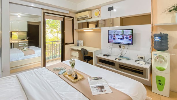 Ein Hotelzimmer mit Bett, Schreibtisch, Computer, Fernseher und Wasserspender.