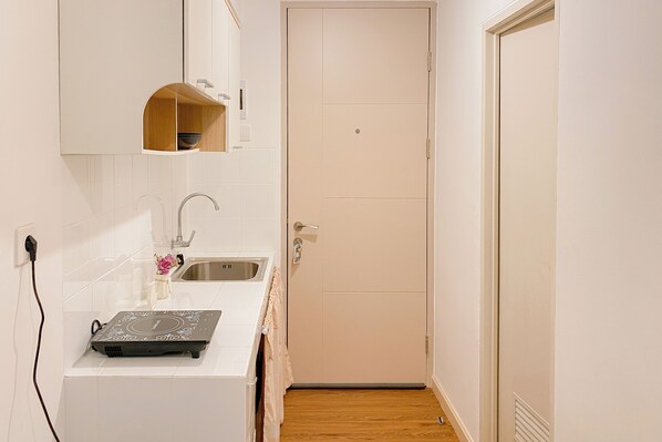A small kitchen with a sink, a countertop, and a door.