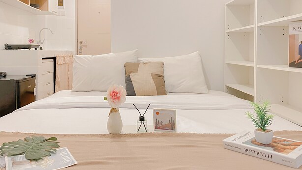 Une chambre d’hôtel bien rangée, avec un lit, une table de chevet et une bibliothèque.