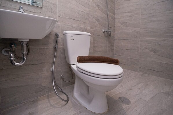 Un baño con lavamanos, inodoro y ducha blancos.