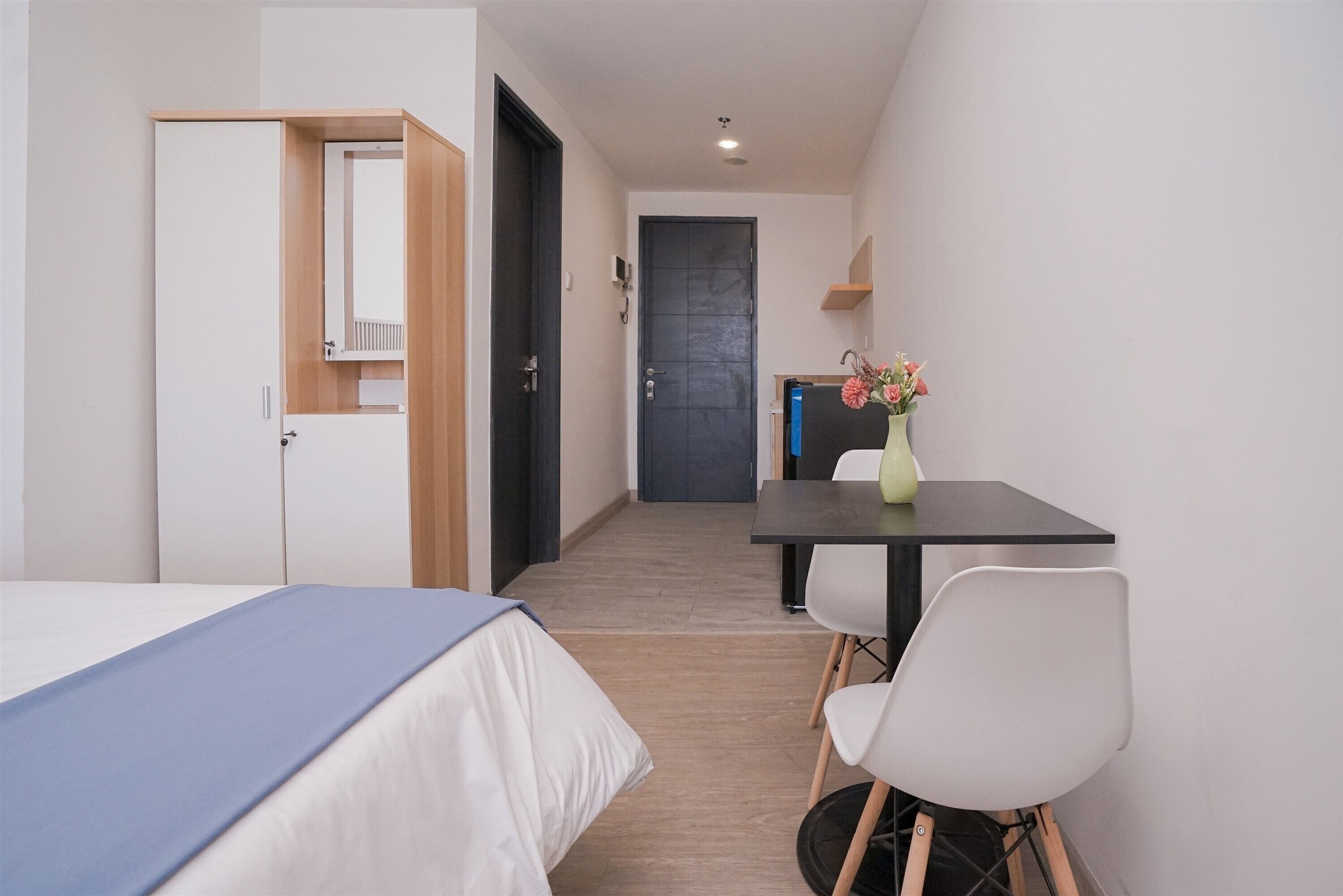 A hotel room with a bed, a desk, a chair, and a door.
