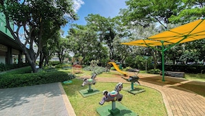 Un parque infantil con un tobogán amarillo, césped verde y un camino de ladrillo.