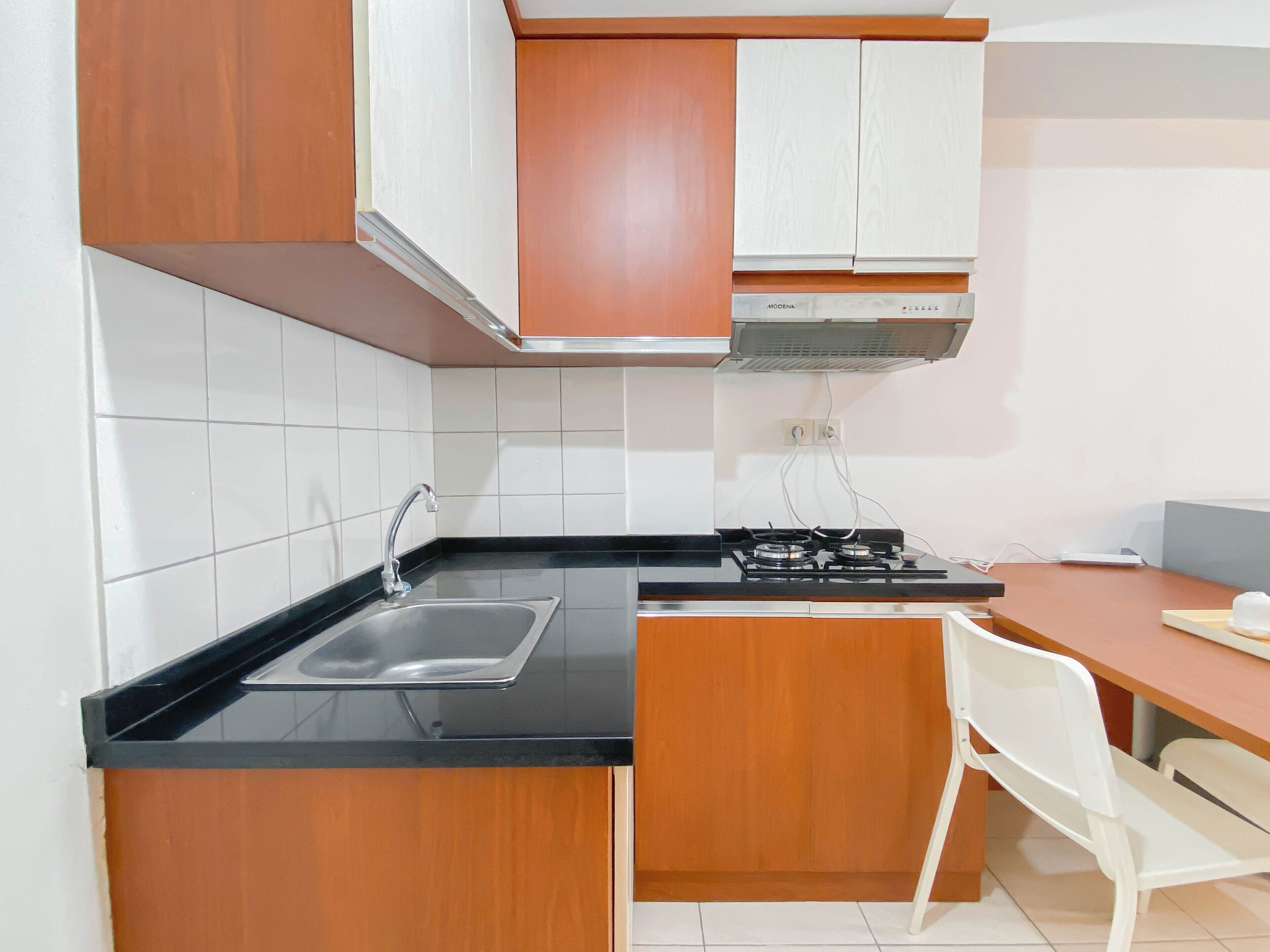 A kitchen with a black countertop, white cabinets, a stainless steel sink, and a gas stove.