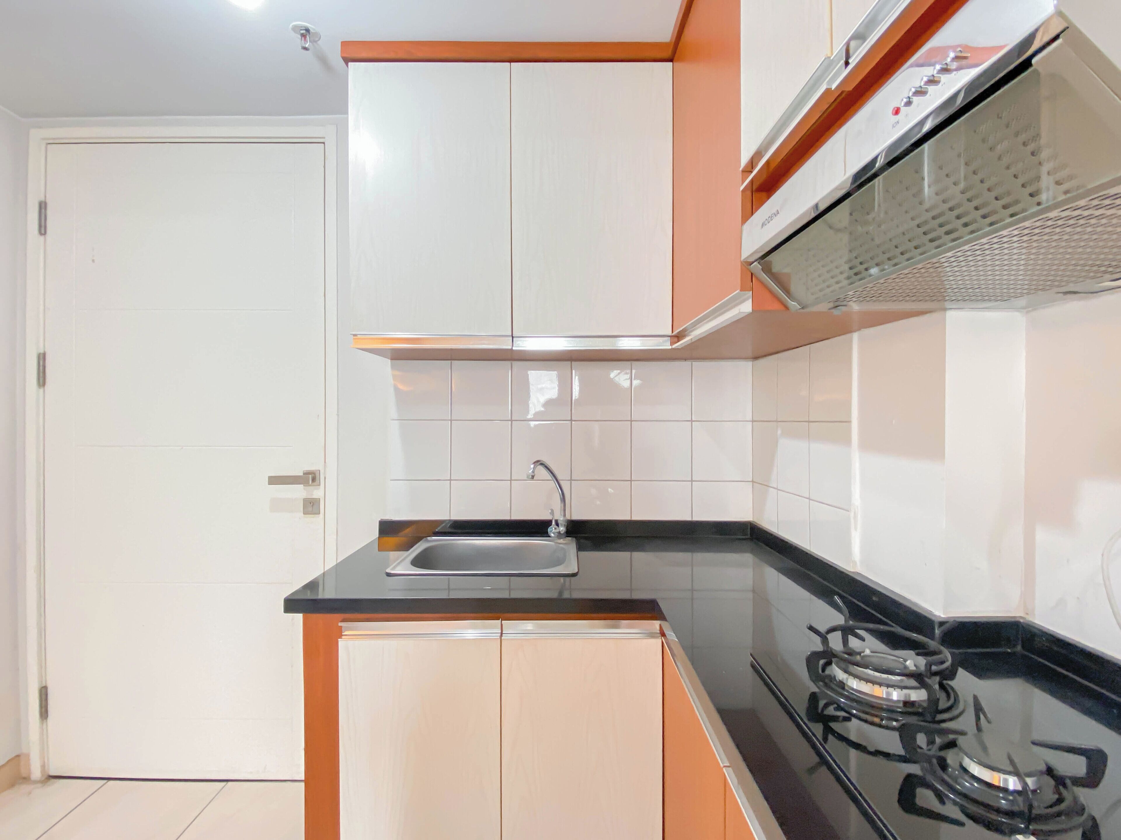 A kitchen with white cabinets, a black countertop, a stainless steel sink, and a gas stove.