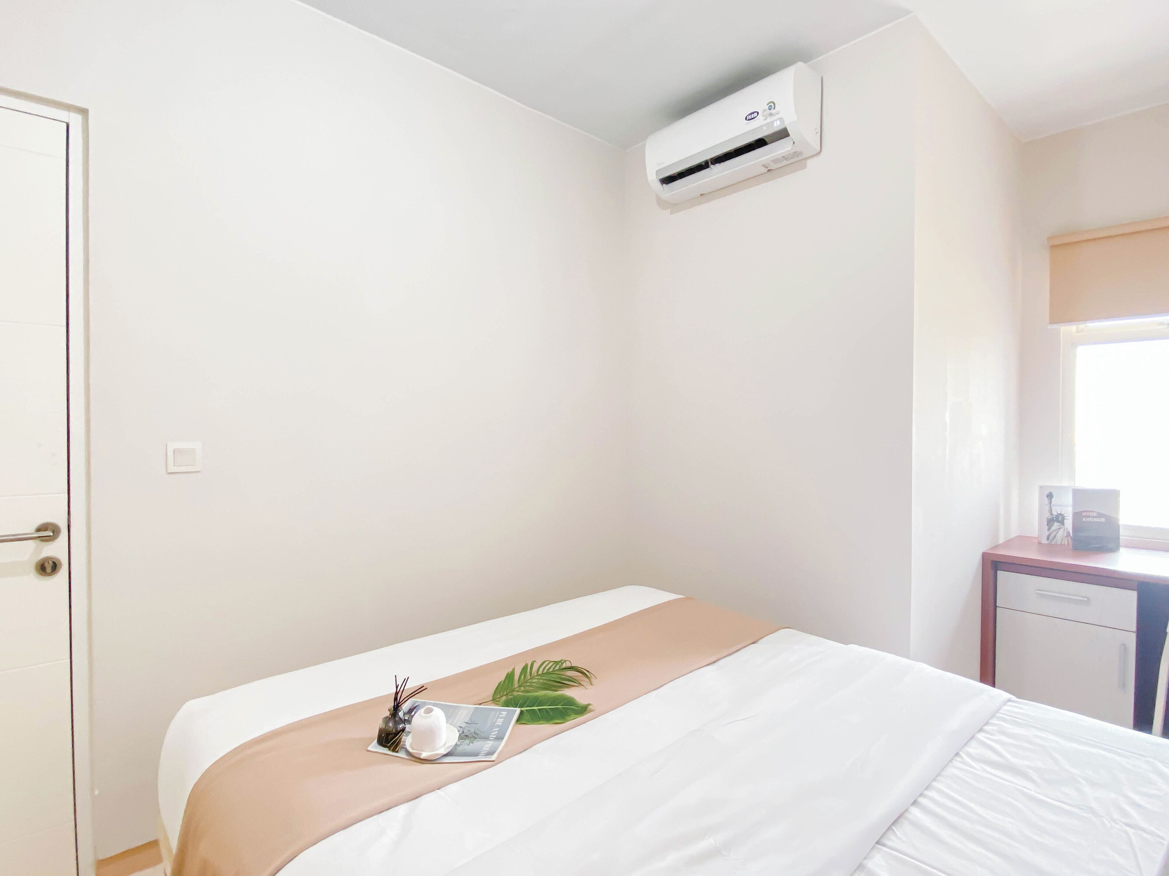 Una habitación de hotel con cama, mesita de noche, ventana y equipo de aire acondicionado.