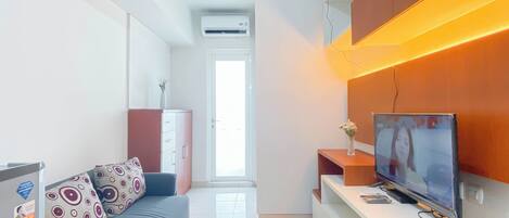Un salon moderne avec un canapé, un téléviseur et un meuble.
