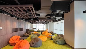 Un intérieur moderne avec un tapis vert, des murs en bois et des fauteuils en forme de haricot de couleur orange.