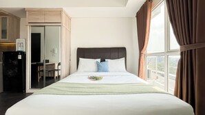 Une chambre d’hôtel avec un lit, un bureau et un réfrigérateur.