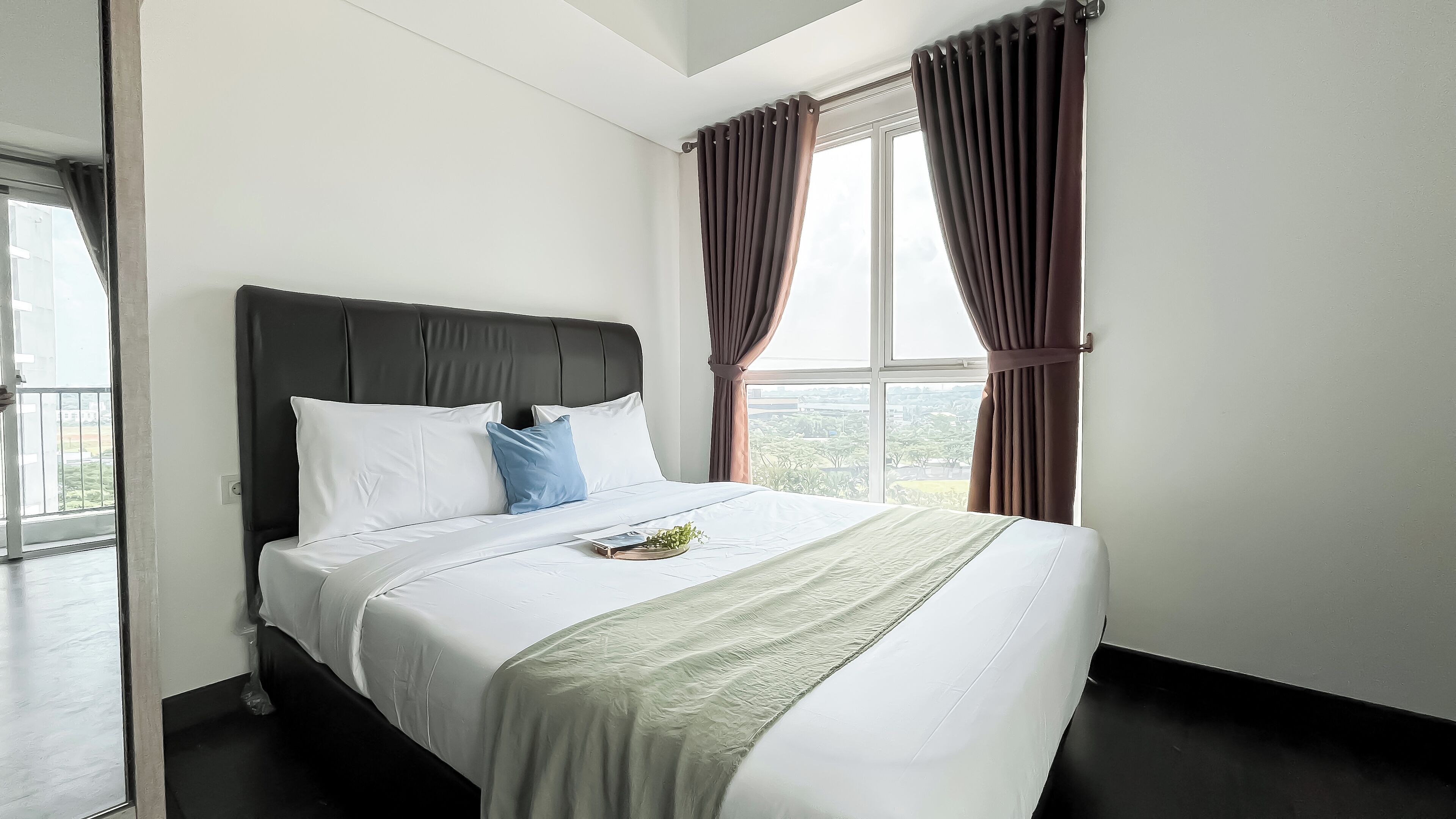 Una habitación de hotel con una cama grande, vistas de la ciudad y un balcón.