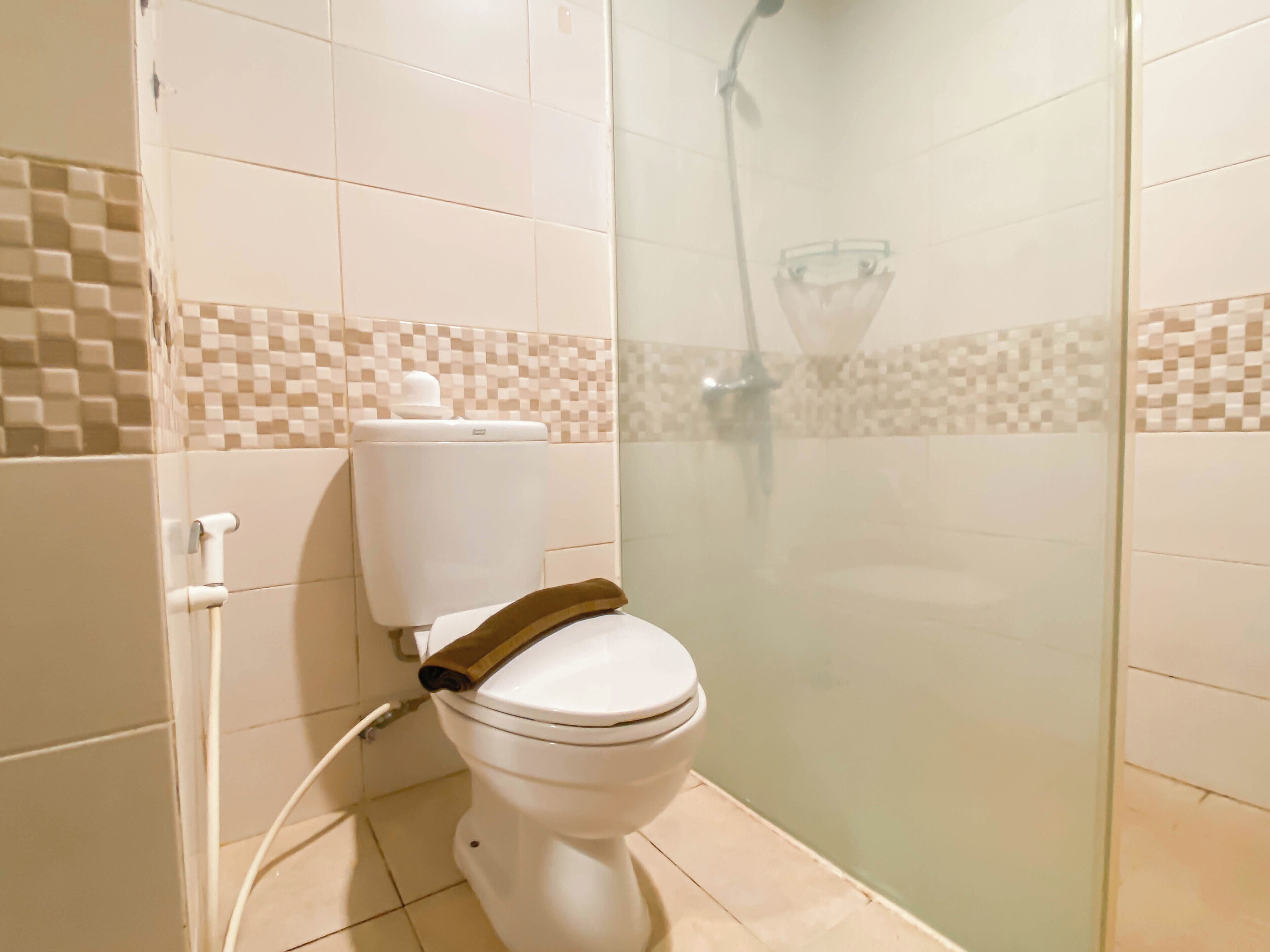 A bathroom with a toilet, a shower, and tiled walls.