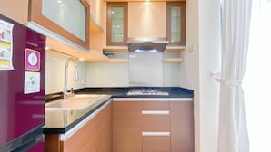 Eine kleine Küche mit Kühlschrank, Spüle, Herd und Schränken.