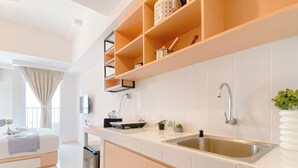 A modern kitchen with white tiles, wooden cabinets, and a stainless steel sink. - Cozy And Enjoy Studio At Tokyo Riverside Pik 2 Apartment (Teluknaga)