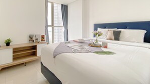 Un dormitorio moderno con una cama grande, un escritorio empotrado y una ventana con cortinas.