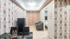 A hotel room with a dining area, a sofa, a bed, and a bathroom with a shower and toilet. - Gorgeous And Homey 1Br Apartment At Podomoro City Deli Medan (Medan)