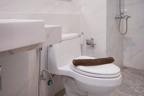Un baño con inodoro blanco, ducha y pared con azulejos de mármol.