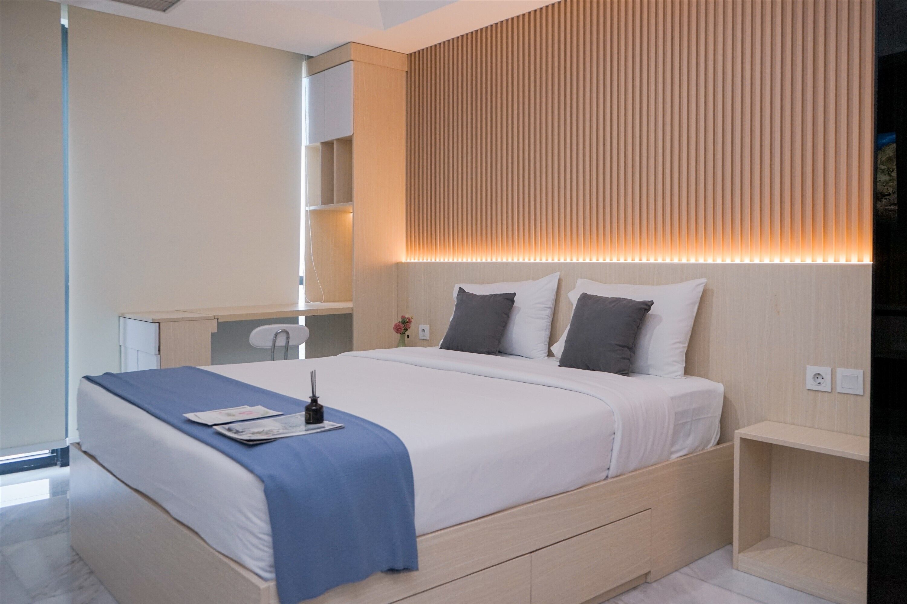 Een moderne slaapkamer met een groot bed, nachtkastjes, een spiegel en een wand van hout.