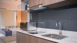 A modern kitchen with a built-in oven, a sink, and a compact refrigerator. - Spacious Studio At Apartment The Smith Alam Sutera (Tangerang)