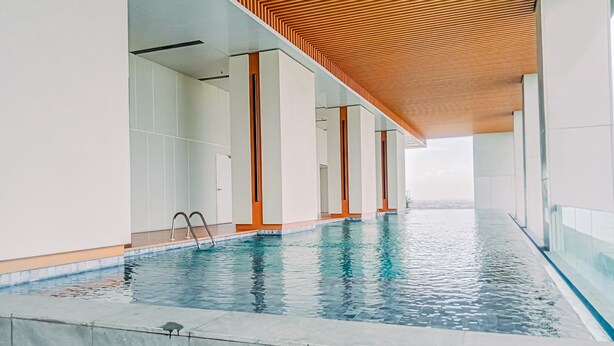 An indoor swimming pool with a wooden ceiling and glass walls. - Spacious Studio At Apartment The Smith Alam Sutera (Tangerang)