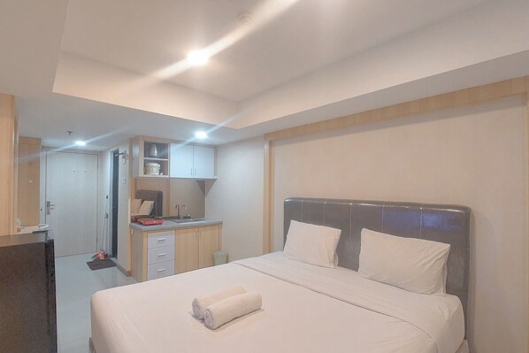 Una habitación de hotel con cama, escritorio, espejo y armario.