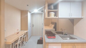 A compact kitchen with a countertop, sink, and cabinets. There is a dining area with chairs and a table.