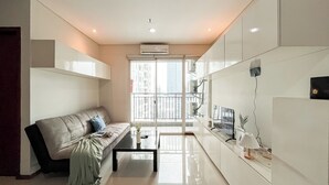 A modern living room with a sofa, coffee table, and a TV. - Nice And Cozy 3Br Apartment At Thamrin Residence (Jakarta)