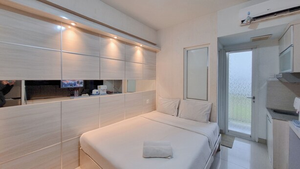 Camera d'albergo moderna con un letto grande, spazio contenitori integrato, televisione e un balcone con porta scorrevole.