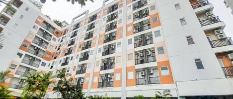 Un edificio residencial de varios pisos con balcones, piscina y zonas verdes circundantes.