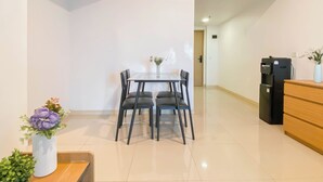 A modern kitchen with a dining table, chairs, a refrigerator, and a wooden cabinet. - Comfy Stay 2Br At Meikarta Apartment (Cikarang)