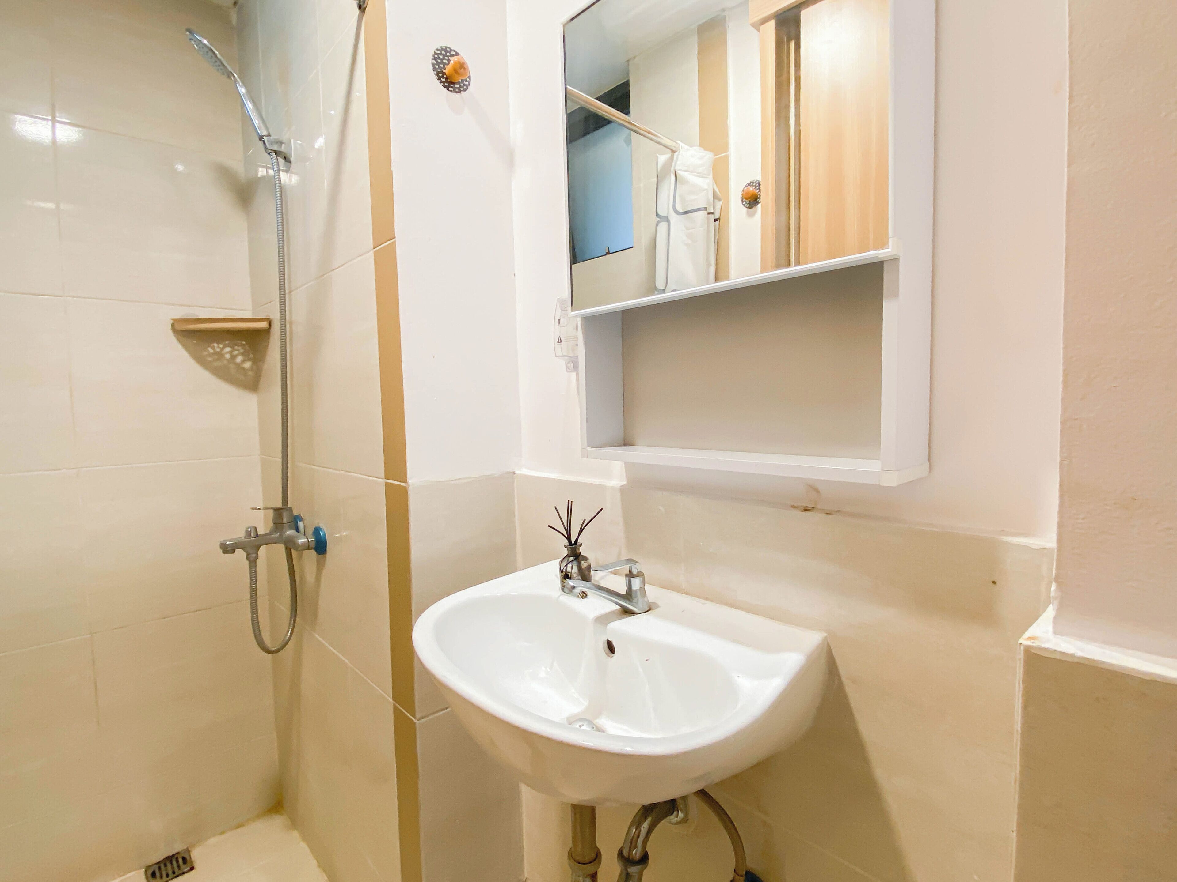 Un baño con ducha, lavamanos y espejo.