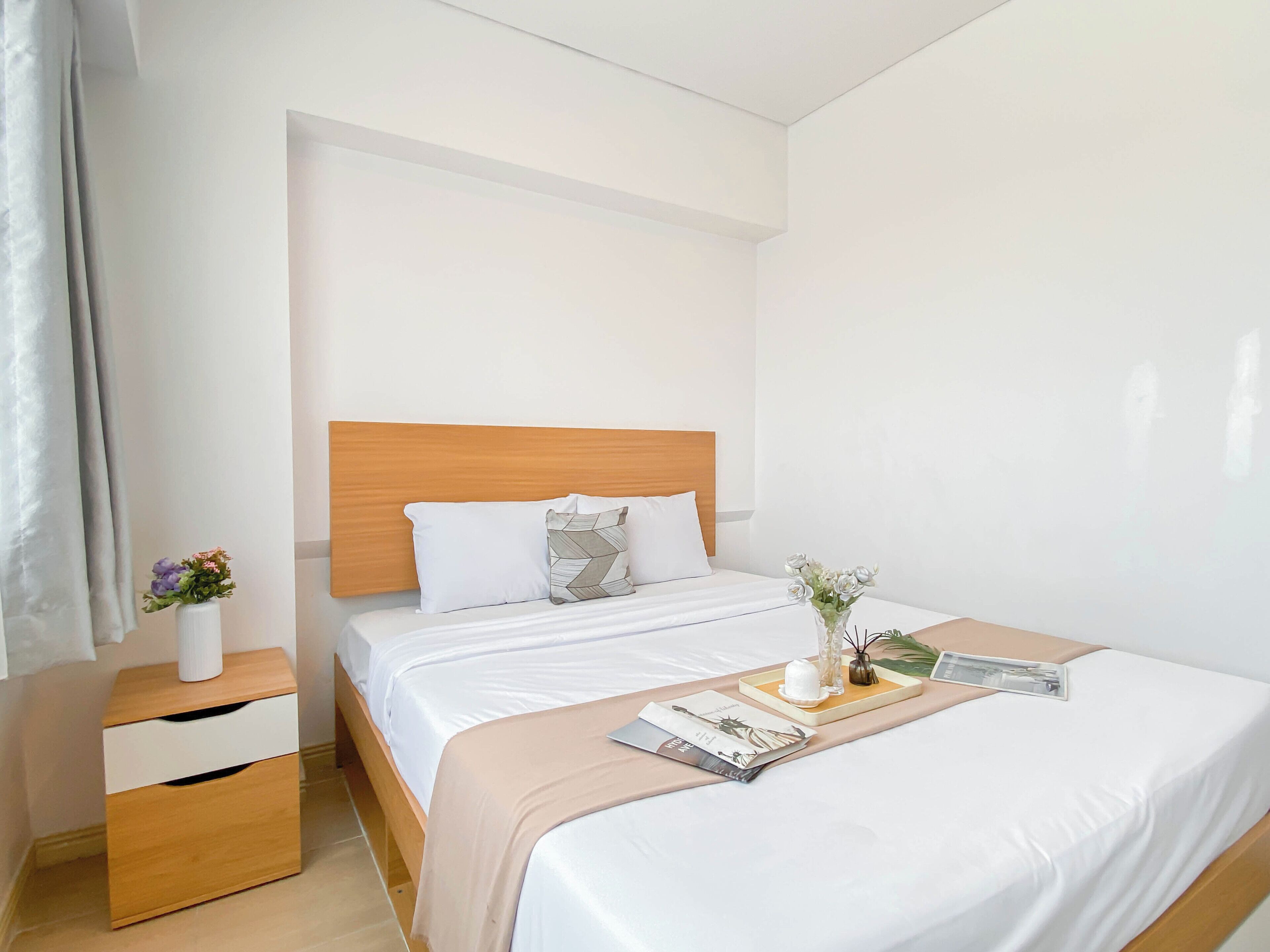 Une chambre d’hôtel bien rangée, avec un lit, une table de chevet et une petite table de nuit.