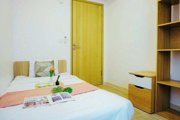 A neatly arranged hotel room with a bed, bedside table, and a wooden wardrobe.