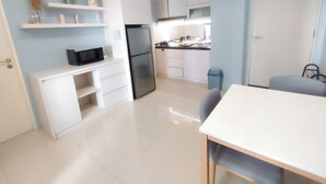 Eine moderne Küche mit weißen Schränken, einem schwarzen Kühlschrank und einer Mikrowelle auf einer weißen Arbeitsplatte.