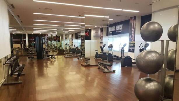 Ein Fitnessstudio mit verschiedenen Trainingsgeräten, darunter Laufbänder und Kraftgeräte.
