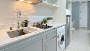 Une cuisine moderne équipée d’une cuisinière à gaz intégrée, d’un évier, d’un lave-vaisselle et d’une machine à laver.