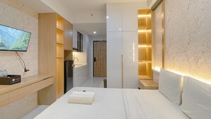 Ein modernes Hotelzimmer mit Bett, Wandfernseher, Holzschrank und Einbauschrank.