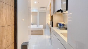Ein modernes Hotelzimmer mit Holzboden, einem Bett, einer kleinen Küchenzeile und einem Badezimmer.