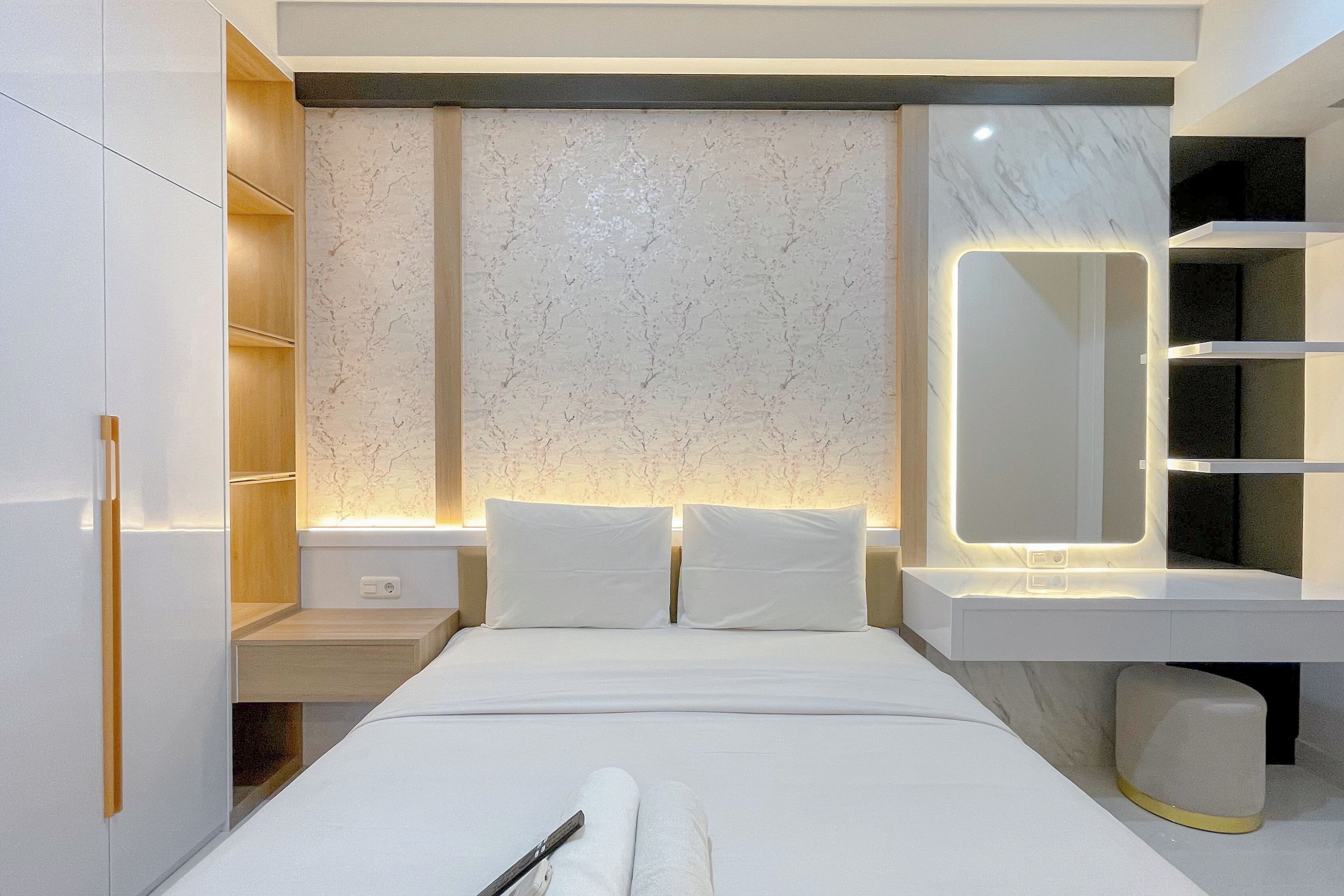 Een moderne hotelkamer met een groot bed, ingebouwde planken, een marmeren accentmuur en een spiegel naast het bed.