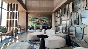 Eine moderne Lobby mit einem großen, abstrakten Gemälde, runder Sitzgelegenheiten und einem gemusterten Boden.