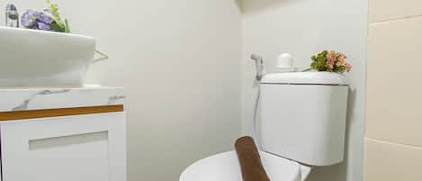A bathroom with a white toilet, a sink with a marble countertop, and a small potted plant on the wall.