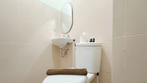 Une salle de bain équipée de toilettes, d’un lavabo et d’un porte-rouleau de papier toilette.