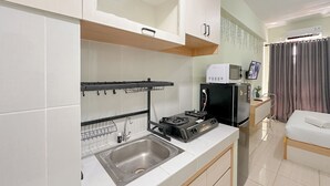 Une cuisine compacte équipée d’un évier, d’une cuisinière et d’un four à micro-ondes. Un petit coin repas avec une table et une chaise est également disponible.