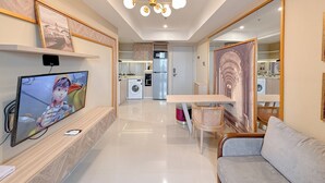 A modern living room with a TV, sofa, and dining area. - New Contemporary 2Br At Grand Sungkono Lagoon Apartment (Surabaya)