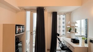 Una camera d'albergo con scrivania, sedia e vista sulla città attraverso la finestra.