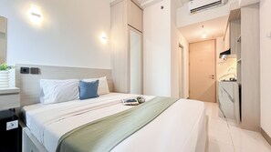 A neatly arranged hotel room with a bed, bedside tables, a mirror, and a wardrobe. - Homey And Restful Studio At Tokyo Riverside Pik 2 Apartment (Teluknaga)