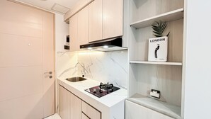 Una cucina moderna con piano di lavoro in marmo, lavello in acciaio inossidabile e piano cottura a gas. Si nota uno scaffale con una pianta in vaso e un cartello con la scritta "LONDON Oxford Street".