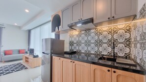 A modern kitchen with wooden cabinets, a black countertop, and a patterned backsplash.