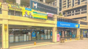 A building with a 'Supermarket' sign, a 'Loan' advertisement, and a 'Meikarta Owners Lounge' sign. - Relaxing Studio Room At Meikarta Apartment (Cikarang)