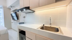 Una cocina moderna con un lavamanos de acero inoxidable, lavavajillas integrado y televisor montado en la pared.
