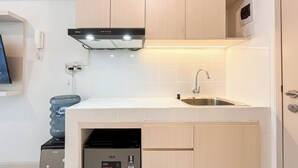 Una cocina compacta con lavavajillas integrado, un lavamanos y una campana extractora.